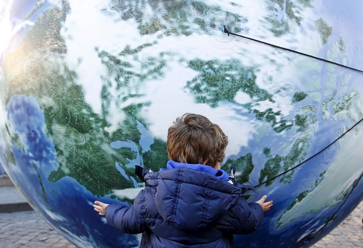 © Reuters. A child embraces a globe shaped balloon during a rally held ahead of the start of the 2015 Paris World Climate Change Conference, known as the COP21 summit, in Rome