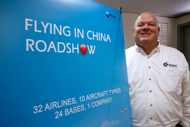 © Reuters. Dave Ross, President and CEO of WASINC International, poses beside a recruitment banner in Hong Kong