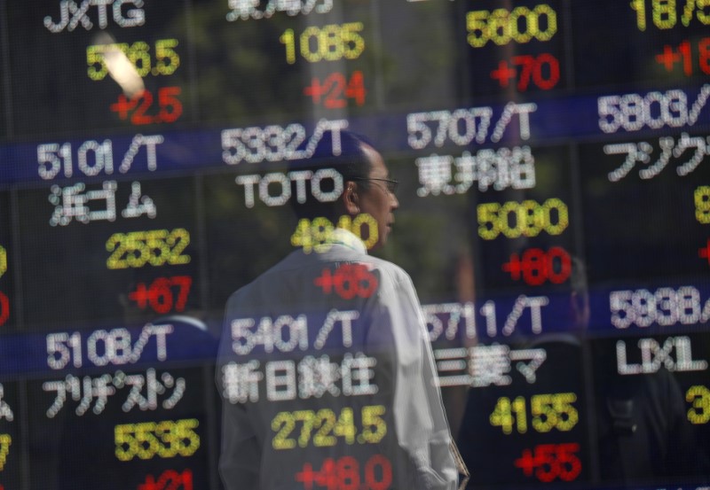 © Reuters. Passersby are reflected in an electronic stock quotation board outside a brokerage in Tokyo