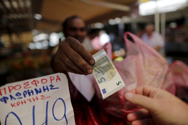 © Reuters. A vendor gives a five Euro bank note back to a customer at the central market in Athens