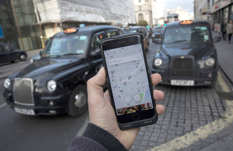 © Reuters. A photo illustration shows the Uber app on a mobile telephone, as it is held up for a posed photograph, with London Taxis in the background, in London
