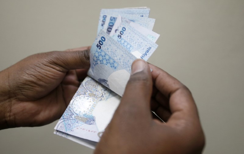 © Reuters. A man counts Qatari riyal notes at a money changer in Doha