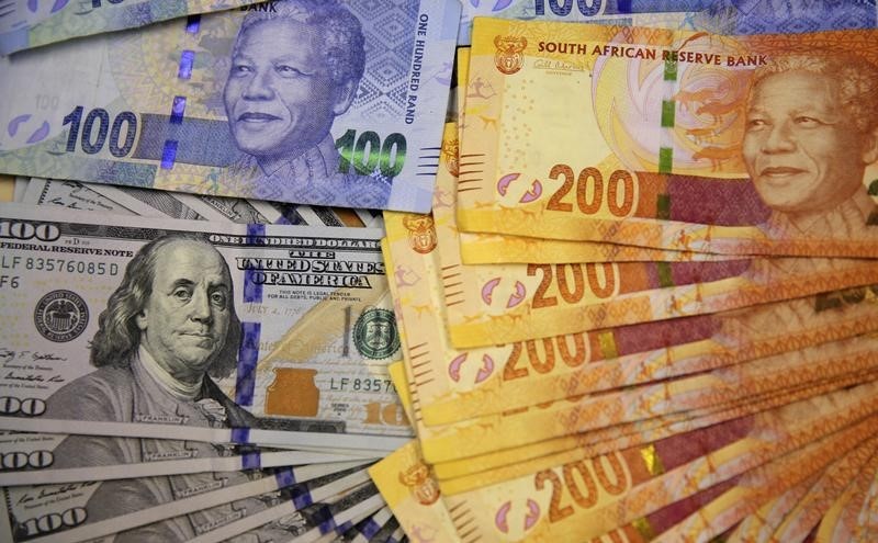 © Reuters. Photo illustration of South African bank notes displayed next to the American dollar notes in Johannesburg