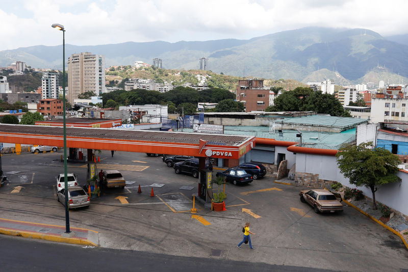 © Reuters. Pedestrians walk next to a gas station of Venezuelan state-owned oil company PDVSA in Caracas