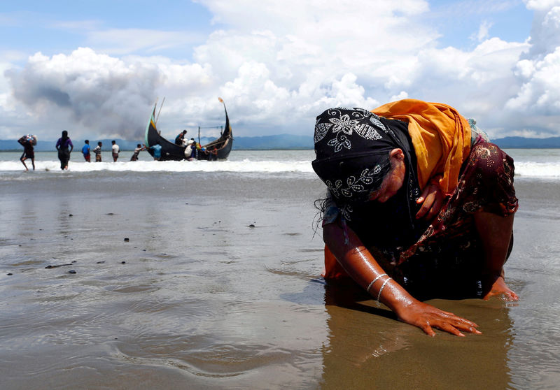 © Reuters. An exhausted Rohingya refugee woman touches the shore after crossing the Bangladesh-Myanmar border by boat through the Bay of Bengal, in Shah Porir Dwip, Bangladesh, September 11.