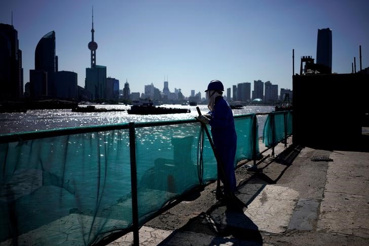 © Reuters. A worker stands on a bank on the Huangpu River near the financial district of Pudong in Shanghai