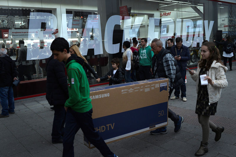 © Reuters. Shoppers carry a television past a sign reading Black Friday outside an electrical store in Barakaldo