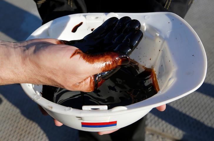 © Reuters. Рабочий демонстрирует образец нефти из скважины на месторождении Приобское
