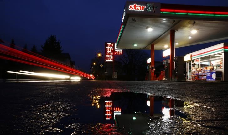 © Reuters. The price indicator of a small gas station is reflected in a puddle on a rainy morning in the village of Klein-Auheim