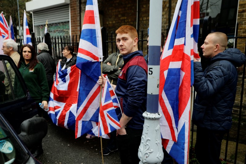 © Reuters. People hold the Union Flag whilst attending a Britain First rally as deputy leader Jayda Fransen looks on, in Rochester