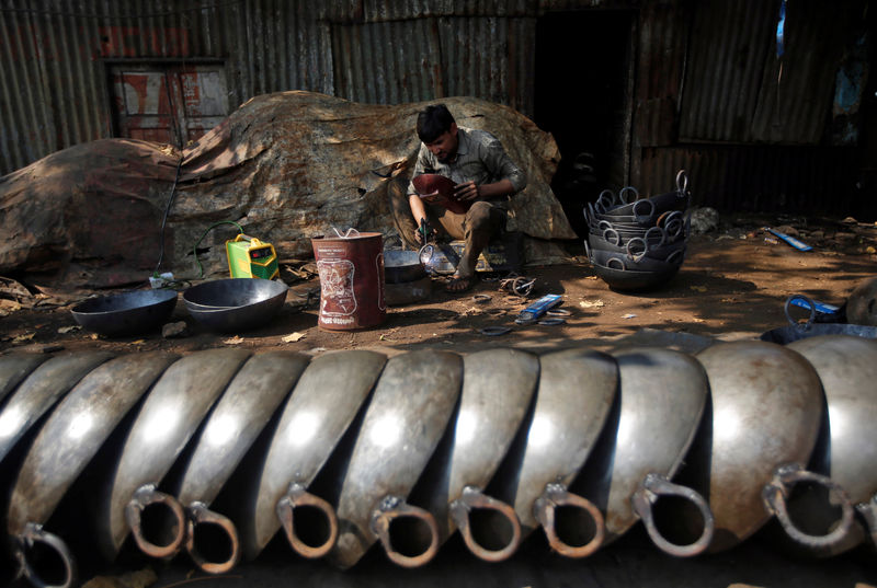 © Reuters. A man makes iron frying pans at his workshop in an industrial area in Mumbai