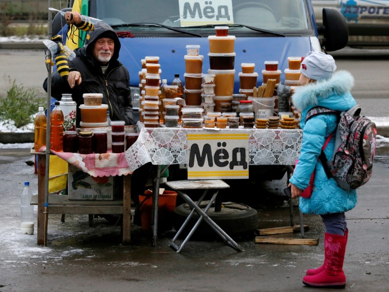 © Reuters. FILE PHOTO -  Honey vendor talks to girl at street market in Krasnoyarsk