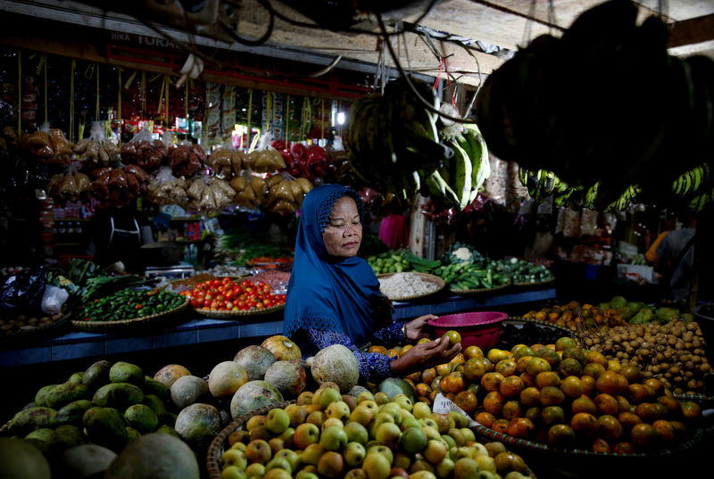 © Reuters. FILE PHOTO: A woman buys fruits at a market in Cikawao village of Majalaya