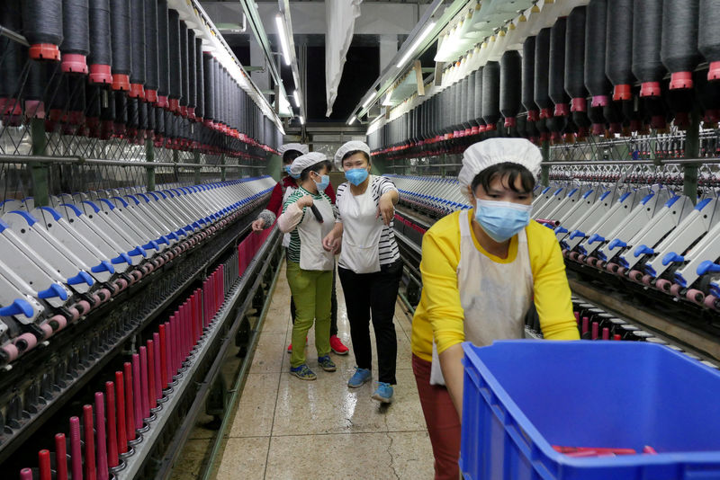 © Reuters. US-busFILE PHOTO: A worker jokes and beckons at her colleague as she rolls away carts of unused tools between rows of spinning machine at a factory owned by Hong Kong's Novetex Textiles Limited in Zhuhai City, Guangdong Province, China