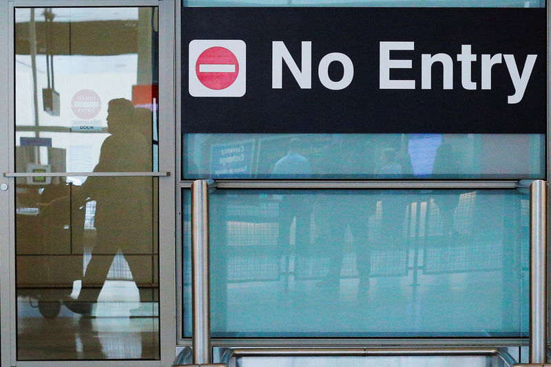 © Reuters. FILE PHOTO: International travelers (reflected in a closed door) arrive on the day that U.S. President Donald Trump's limited travel ban, approved by the U.S. Supreme Court, goes into effect, at Logan Airport in Boston