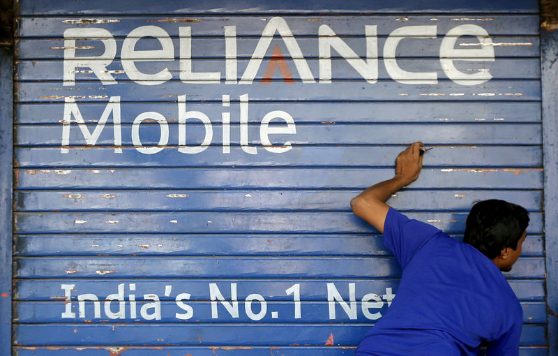 © Reuters. FILE PHOTO: A man opens the shutter of a shop painted with an advertisement of Reliance Communications in Mumbai