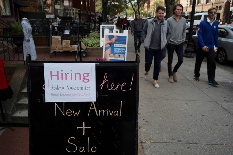 © Reuters. FILE PHOTO: Pedestrians pass a sign advertising a sale and a job opening at a shop on Newbury Street in Boston
