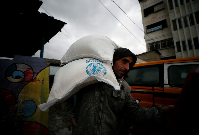 © Reuters. A Palestinian man carries sacks of flour outside a United Nations food distribution center in Al-Shati refugee camp in Gaza City