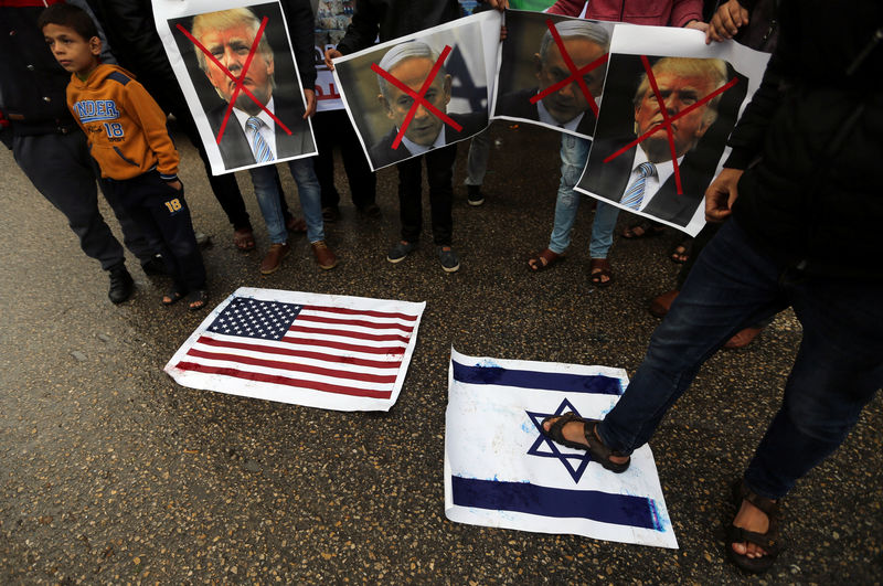 © Reuters. A Palestinian man steps on a representation of an Israeli flag as other demonstrators hold crossed out posters of Netanyahu and Trump during a protest against the U.S. intention to move its embassy to Jerusalem, in Rafah in the southern Gaza Strip