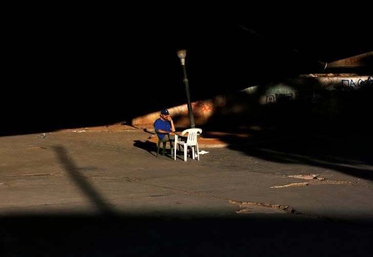 © Reuters. Michael, a 36-year-old unemployed clerk, sits in the sun near a bridge in central Athens