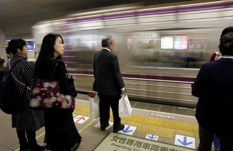 © Reuters. Commuters wait for a train in Osaka