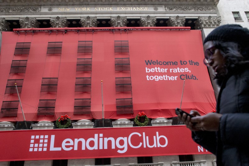 © Reuters. FILE PHOTO - A woman looks at her phone as she passes by a Lending Club banner on the facade of the the New York Stock Exchange