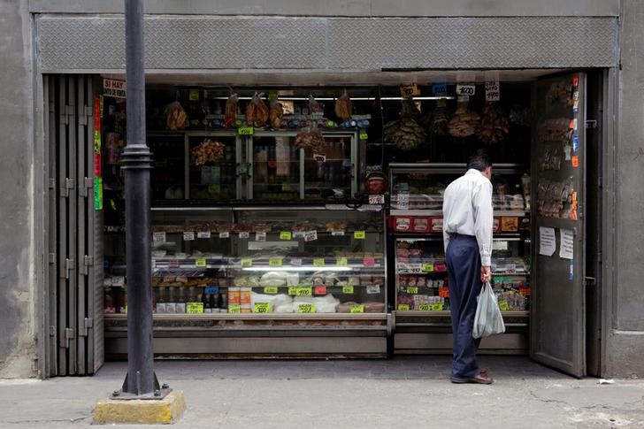 © Reuters. FILE PHOTO - A man looks at prices in a grocery store in downtown Caracas