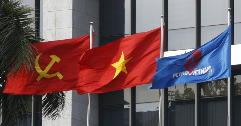 © Reuters. Flag of PetroVietnam flutters next to Vietnamese national flag and Communist Party flag in front of the headquarters of PetroVietnam in Hanoi