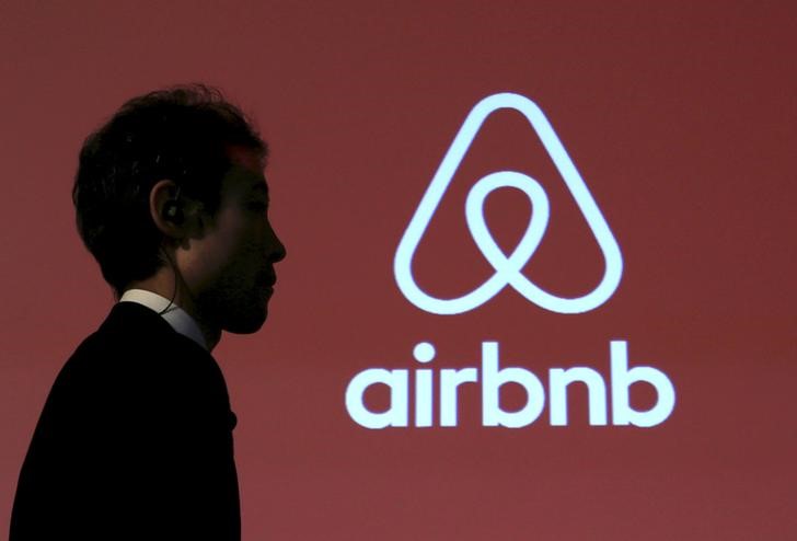 © Reuters. Homem caminha diante de logo do Airbnb durante coletiva de imprensa em Tóquio, Japão