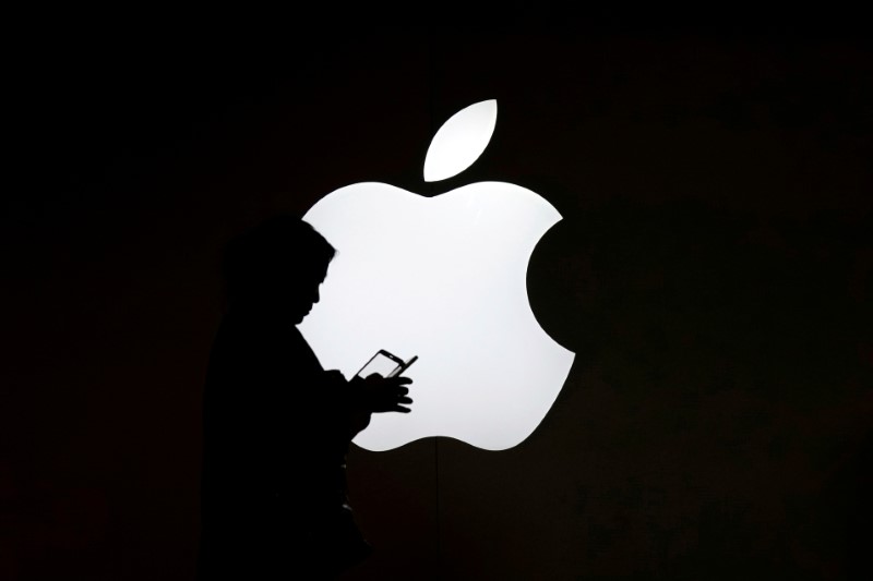 © Reuters. FILE PHOTO - A woman looks at the screen of her mobile phone in front of an Apple logo outside its store in Shanghai