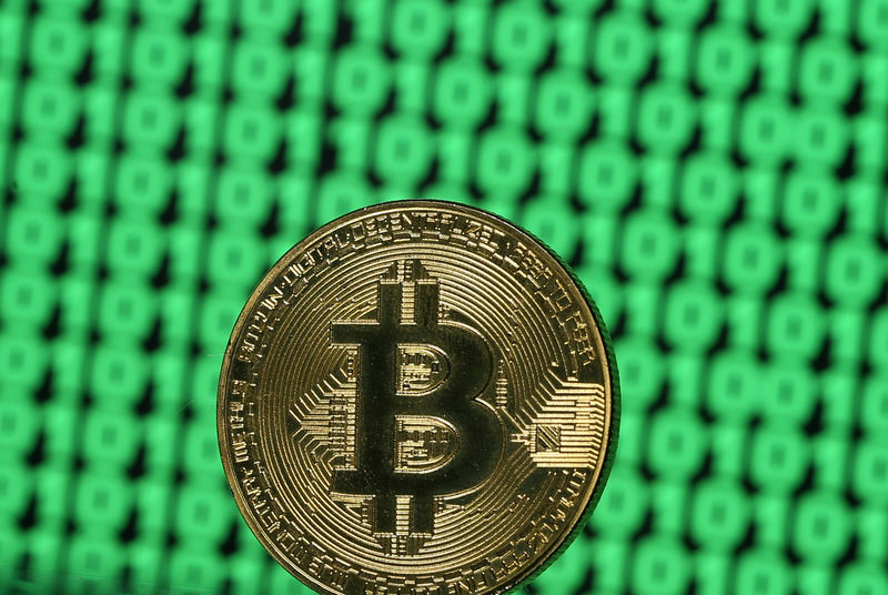 © Reuters. FILE PHOTO - Bitcoin token is seen placed on a monitor that displays binary digits in this illustration picture