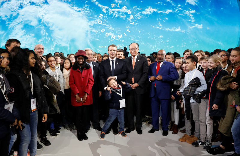 © Reuters. French President Emmanuel Macron poses with children after the closing speech of the Plenary Session of the One Planet Summit at the Seine Musicale event site on the Ile Seguin in Boulogne-Billancourt