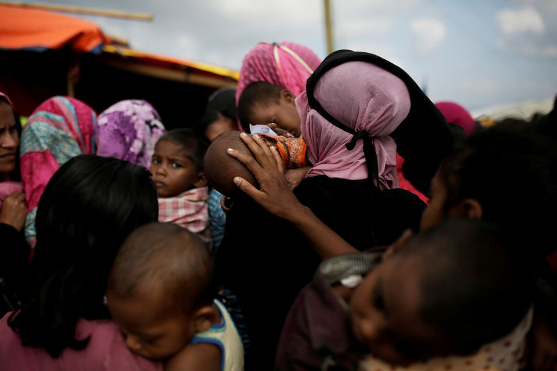 © Reuters. A woman calms a baby as Rohingya refugees line up for a food supply distribution at the Kutupalong refugee camp near Cox's Bazar