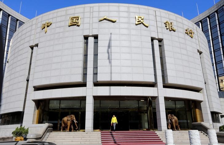 © Reuters. FILE PHOTO - A woman walks out of the headquarters of PBOC in Beijing