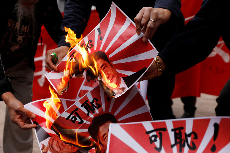 © Reuters. Protesters burn images of the Rising Sun Flag featuring a portrait of Japan's Prime Minister Shinzo Abe in Hong Kong