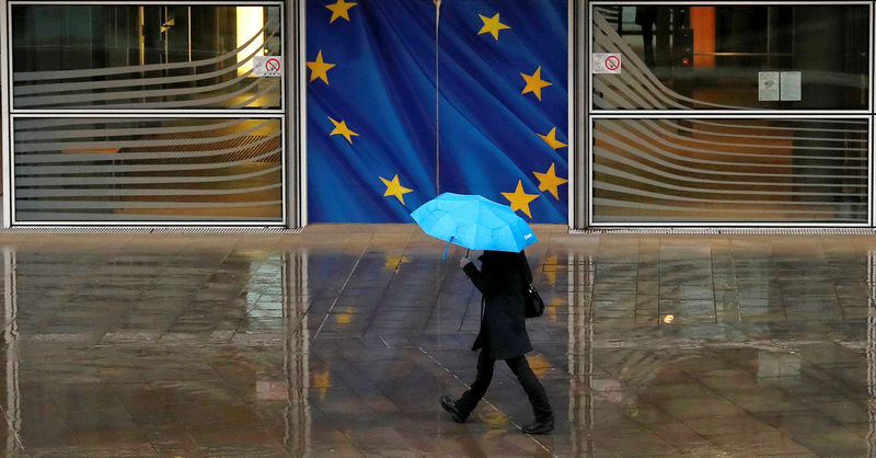 © Reuters. A woman holds an umbrella as she walks past the flag of the European Union outside the European Commission in Brussels, Belgium.