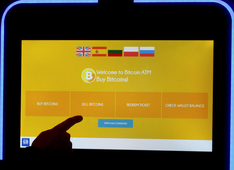 © Reuters. FILE PHOTO - A man touches a screen of a bitcoin ATM in Vilnius