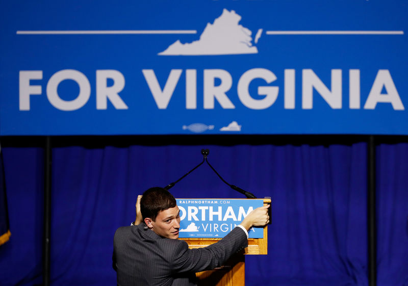 © Reuters. FILE PHOTO: A campaign worker adjusts a podium sign at the election night rally for Democratic gubernatorial candidate Ralph Northam in Fairfax