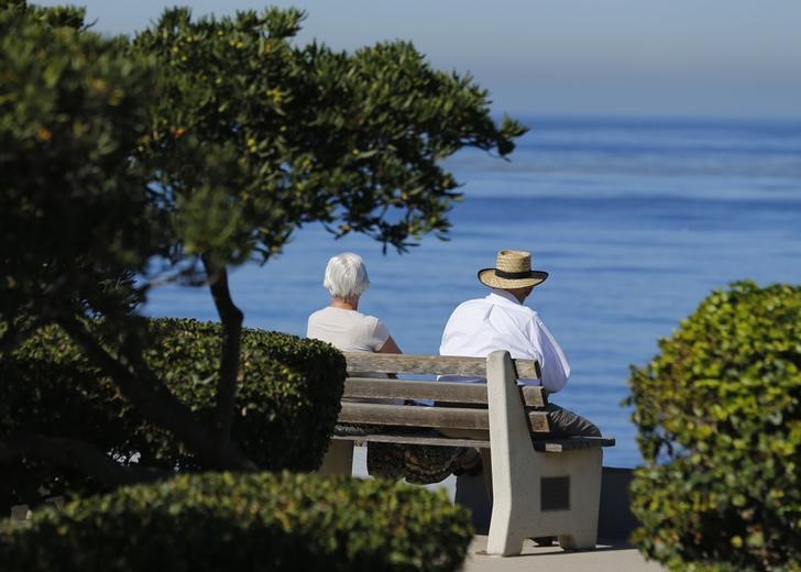 © Reuters. An elderly couple looks out at the ocean as they sit on a park bench in La Jolla, California