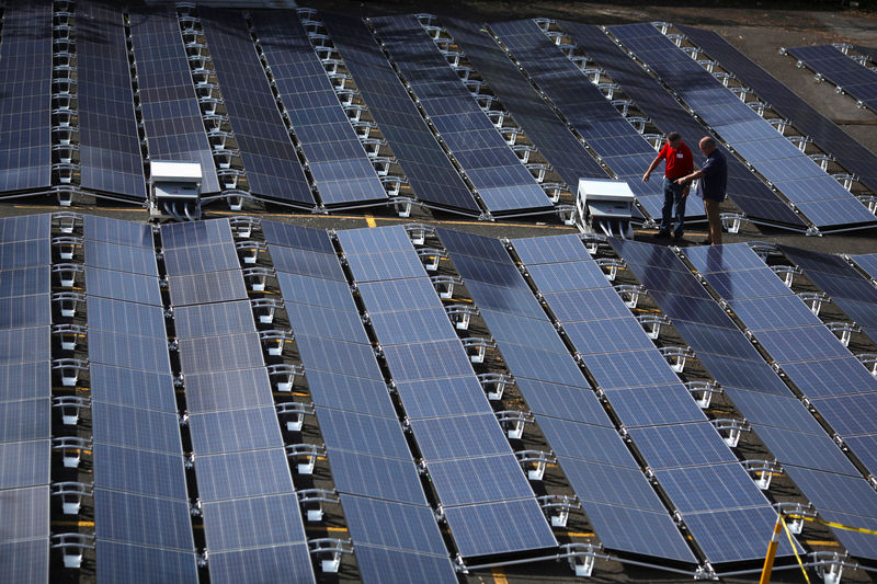 © Reuters. FILE PHOTO: Men gesture next to solar panels set up by Tesla, at the  San Juan Children's Hospital, after the island was hit by Hurricane Maria in September, in San Juan