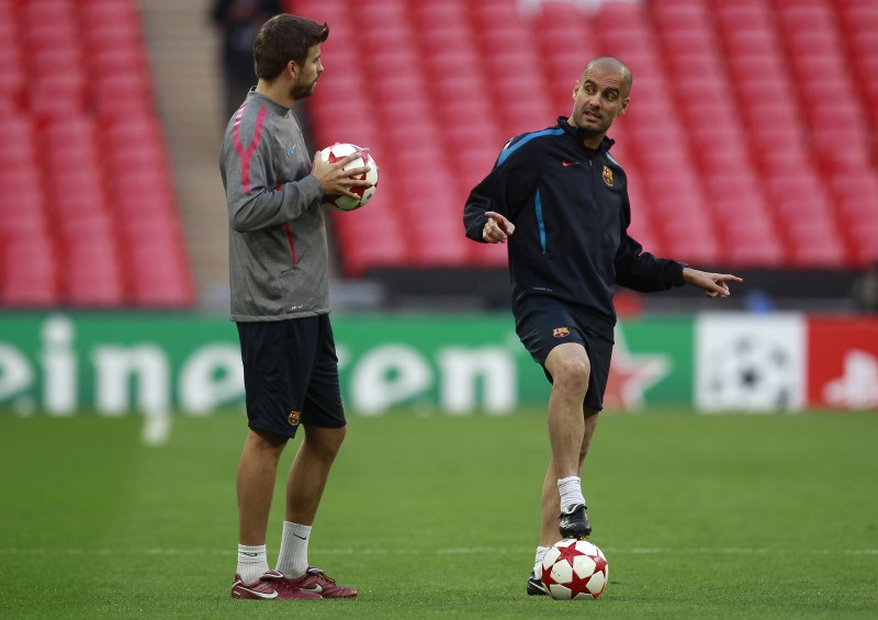 © Reuters. El exentrenador del Barcelona Josep Guardiola (dcha) habla con el defensa Gerard Piqué durante un entrenamiento en el estadio de Wembley en Londres.