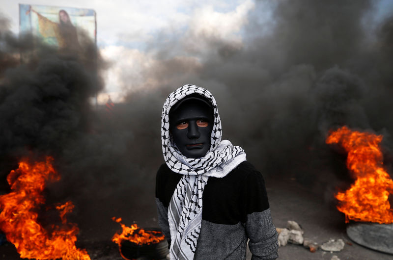 © Reuters. Palestinian demonstrator stands near burning tires during clashes with Israeli troops at a protest near the West Bank city of Nablus