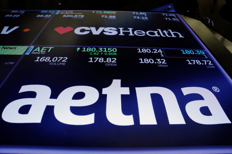 © Reuters. Logos of CVS and Aetna are displayed on a monitor above the floor of the New York Stock Exchange shortly after the opening bell in New York