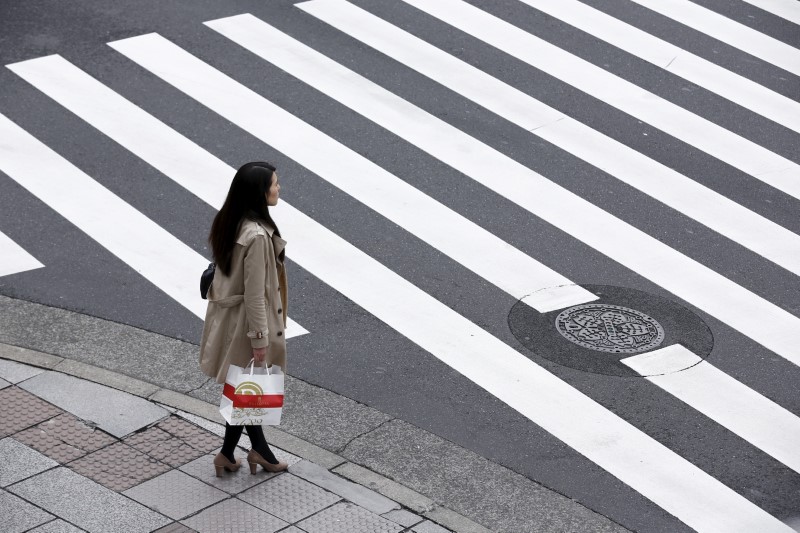 © Reuters. A woman holds a shopping bag as she waits at a pedestrian crossing in the Ginza district in Tokyo