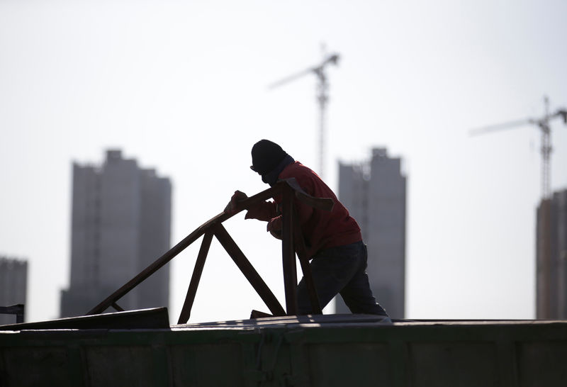© Reuters. A man works near apartment blocks under construction on the outskirts of Beijing