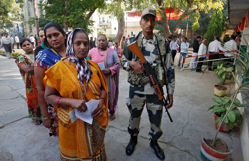 © Reuters. A BSF soldier stands guard as women wait to cast their votes at a polling station during the last phase of Gujarat state assembly election on the outskirts of Ahmedabad