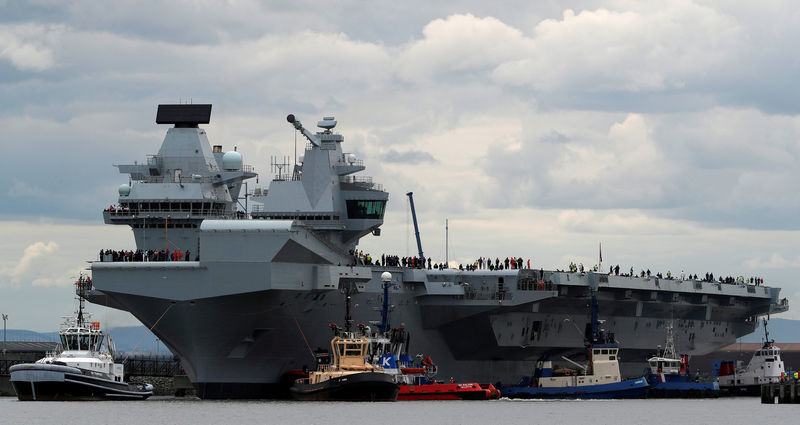 © Reuters. FILE PHOTO: The British aircraft carrier HMS Queen Elizabeth is pulled from its berth by tugs before its maiden voyage, in Rosyth, Scotland
