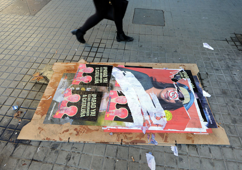 © Reuters. People walk past campaign poster showing ousted Catalan President Carles Puigdemont  ahead of regional elections in Barcelona