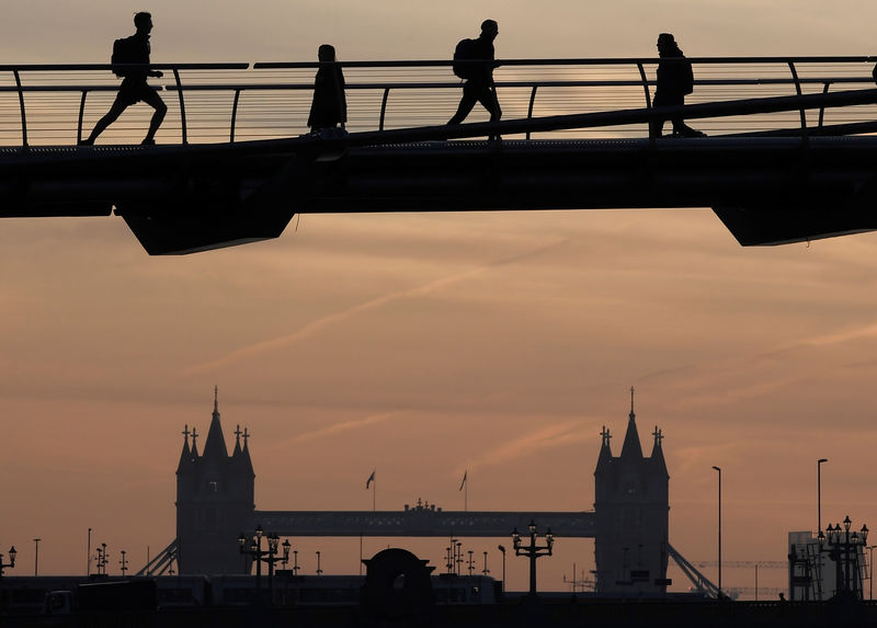 © Reuters. Workers cross the Millennium footbridge at dawn with Tower Bridge seen behind in London