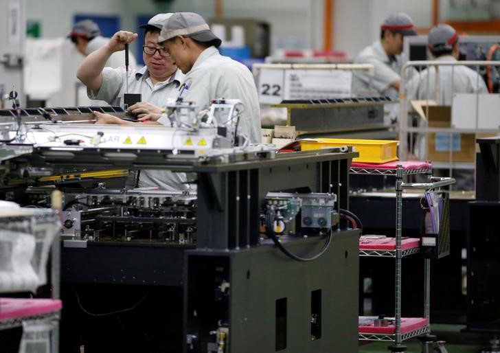 © Reuters. FILE PHOTO: Employees are seen by their workstations at a printed circuit board assembly factory in Singapore